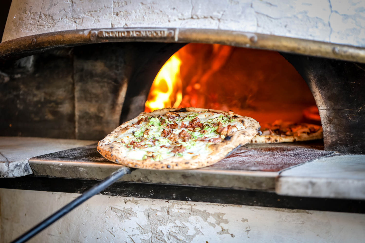 Photo of a pizza being placed in an oven